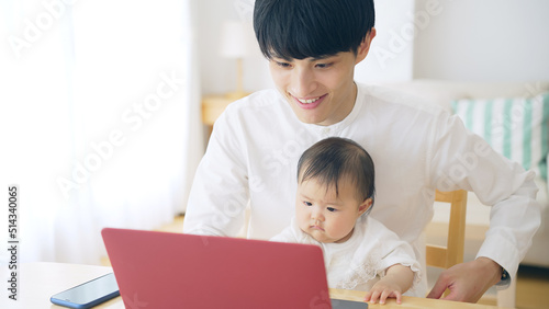 赤ちゃんを抱っこしながら自宅で仕事する男性