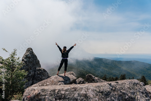 A girl on top of Mount Pidan looks at a beautiful mountain valley in the fog in summer. Travel and tourism. Hiking