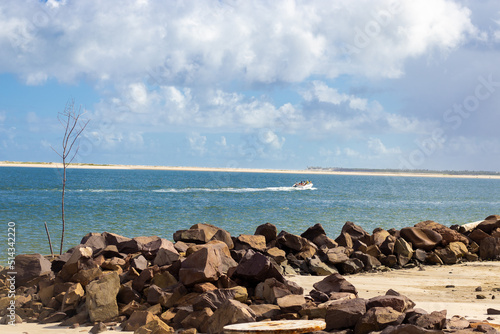 Mar com costa de areia e barco para passear no dia ensolarado