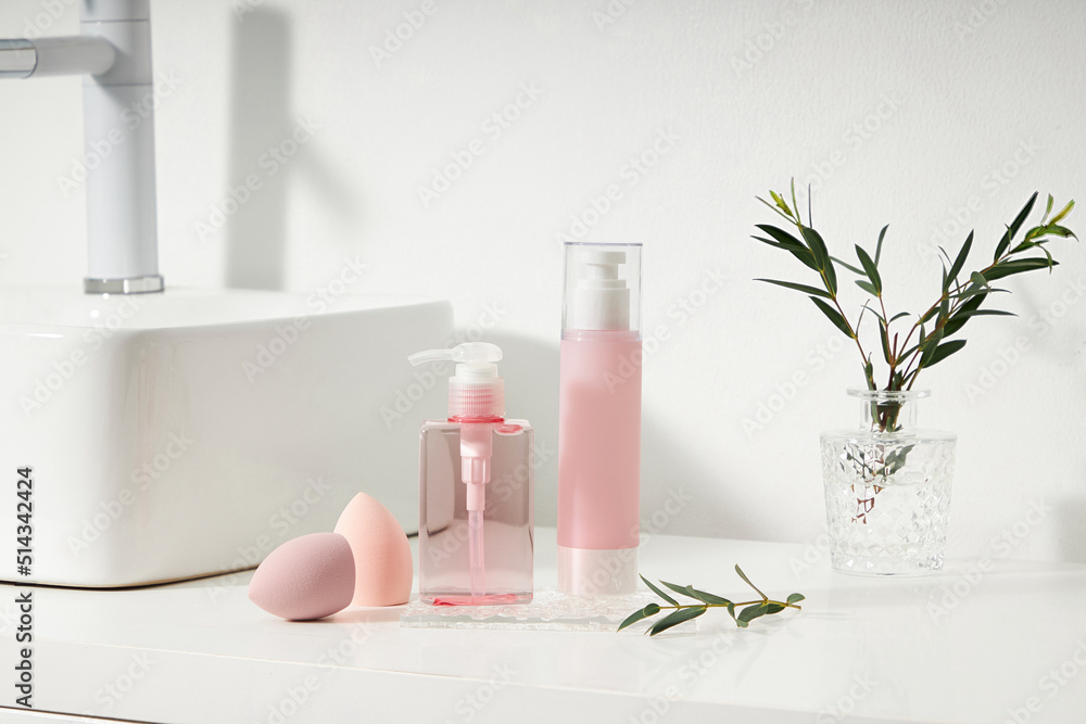 Cosmetics product and cotton towels, cottons pad with green plant on white table inside a bathroom background ceramic. Cosmetics product and cotton towels, cottons pad with green plant on white table inside a bathroom background ceramic.