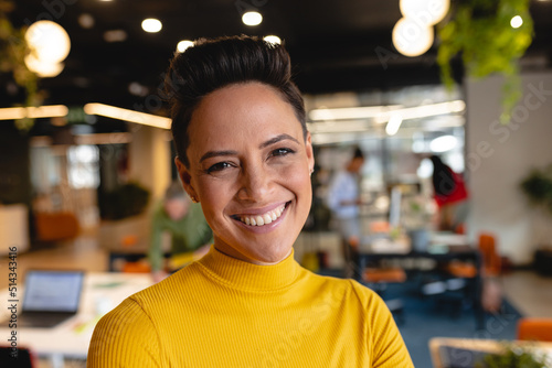 Portrait of smiling young biracial businesswoman in creative office photo
