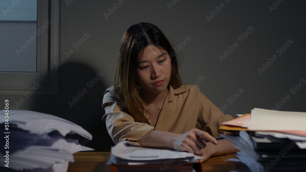 Asian businesswoman or freelancer working hard at the night looking the laptop digital tablet and document in workplace at late overtime deadline, Stressed busy and exhausted of work at home. Asian businesswoman or freelancer working hard at the night looking the laptop digital tablet and document in workplace at late overtime deadline, Stressed busy and exhausted of work at home.