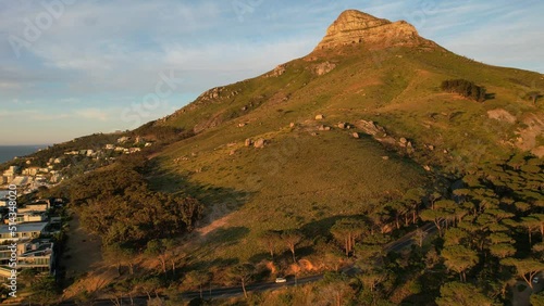 Car driving towards Pipe Track and Lions Head in background at sunset in Cape Town, aerial