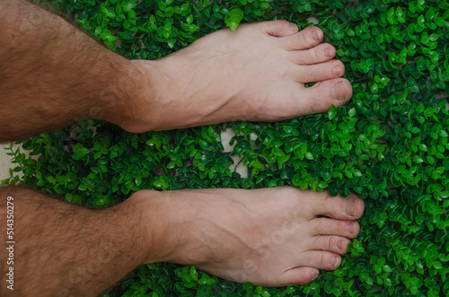 male hairy legs without shoes on green grass