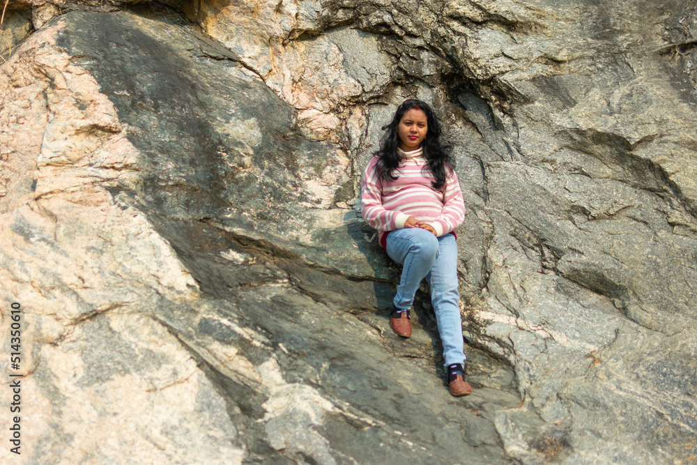 an Indian young woman sitting on a mountain rock peacefully in winter and enjoy the sunlight.