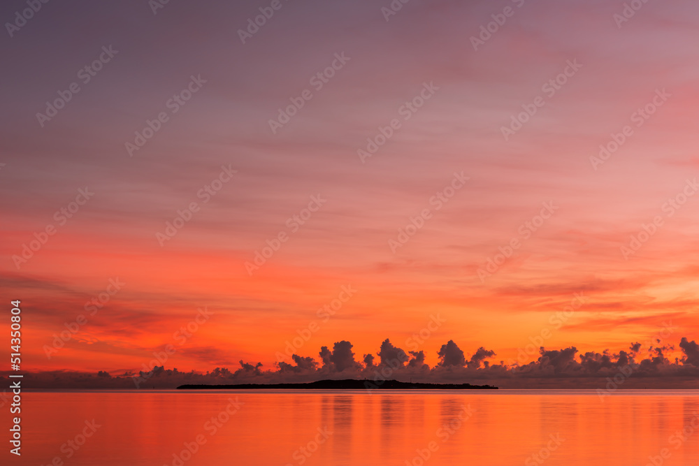 Naklejka premium Peaceful sunrise, colorful sky and sea, island on horizon.