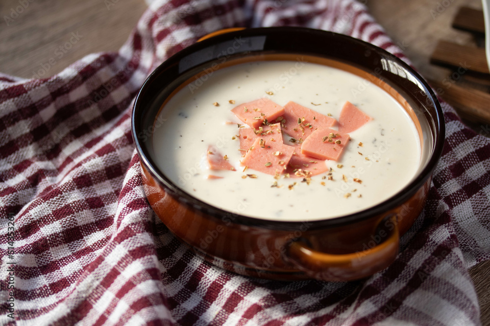 cheese soup with vegetables and ham with toast close-up on the table. horizontal sprinkle oregano in brown bowl. cheese soup with vegetables and ham with toast close-up on the table. horizontal sprinkle oregano in brown bowl.