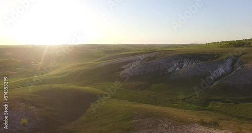 a beautiful girl is standing in a dress on a hill against the backdrop of sunset