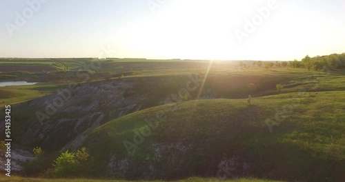 a beautiful girl is standing in a dress on a hill against the backdrop of sunset