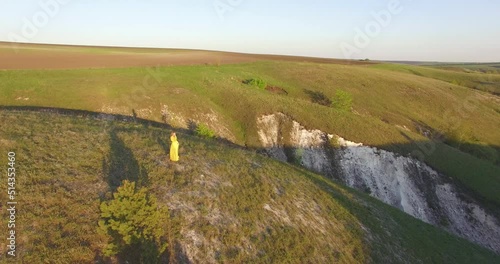 a beautiful girl is standing in a dress on a hill against the backdrop of sunset