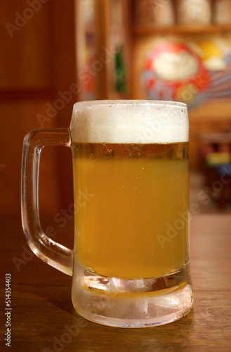 Closeup of a glass of mouthwatering chilled draft beer on wooden table
