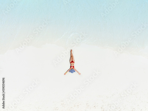 Above view with woman body in bikini sunbathing as laying on the  beach, blue sea water in background -Summer fashion concept