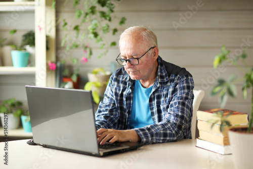 elderly man working on computer while sitting at home © naumenkoe