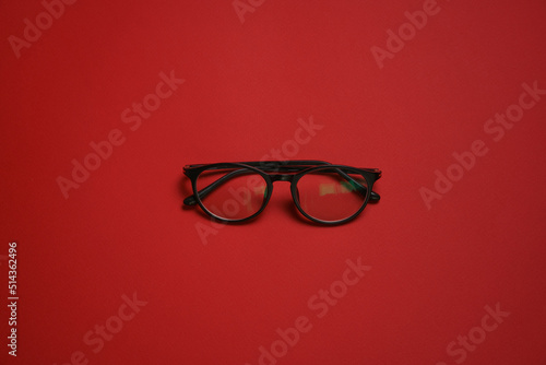 Plastic card style fashion glasses style isolated on dark red background.