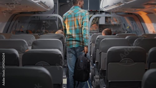 Diverse passengers boarding on airplane to fly in economy class, being seated by flight attendant to travel on vacation trip. Talking to stewardess in plane, flying with airline crew.