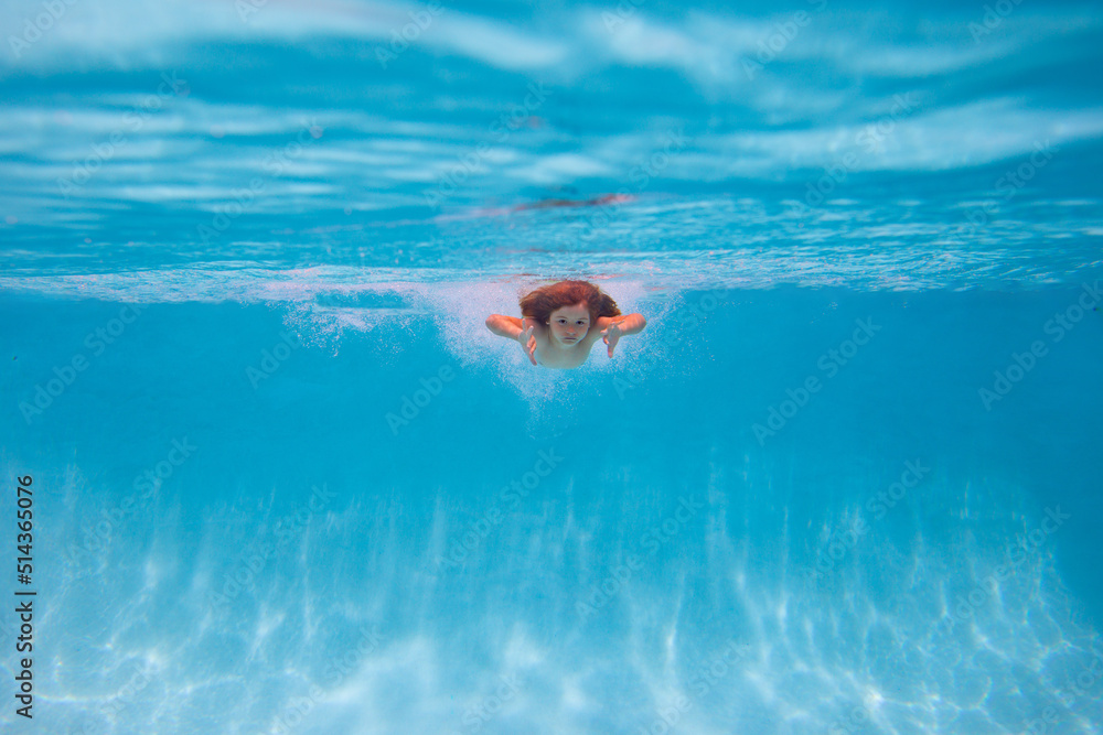Young boy swim and dive underwater. Under water portrait in swim pool. Child boy diving into a swimming pool. Kids holidays and vacation concept. Summer kids.