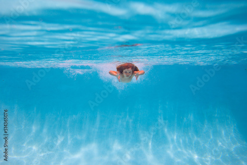 Young boy swim and dive underwater. Under water portrait in swim pool. Child boy diving into a swimming pool. Kids holidays and vacation concept. Summer kids.