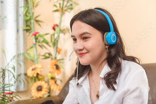 A young sales and reservation agent working from home. An asian lady with a part-time remote job. Work requiring a headset. photo