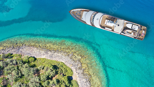 Aerial drone top down photo of luxury yacht with wooden deck anchored in paradise exotic emerald bay resembling a blue lagoon © aerial-drone