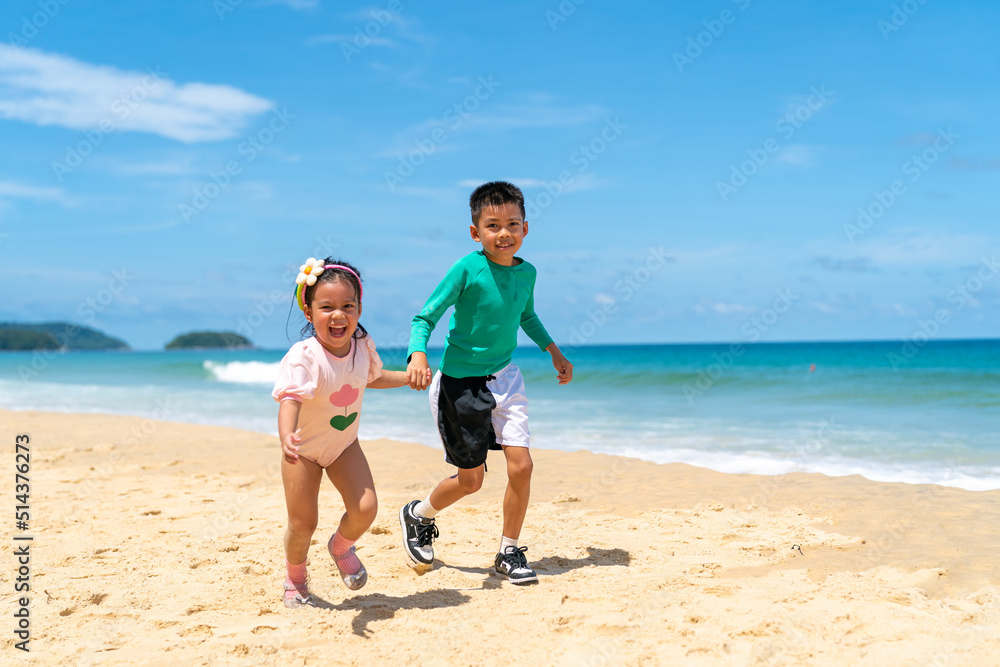 Happy Asian family on beach vacation. Little child boy and girl sibling playing sea water at the beach in summer sunny day. Children kid enjoy and fun outdoor activity lifestyle together at the sea Happy Asian family on beach vacation. Little child boy and girl sibling playing sea water at the beach in summer sunny day. Children kid enjoy and fun outdoor activity lifestyle together at the sea