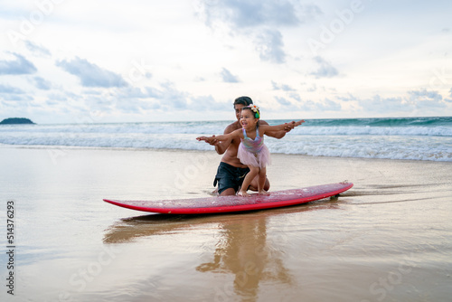 Photography Happy Asian family grandfather teaching little grandchild girl surfing on surfboard at the beach