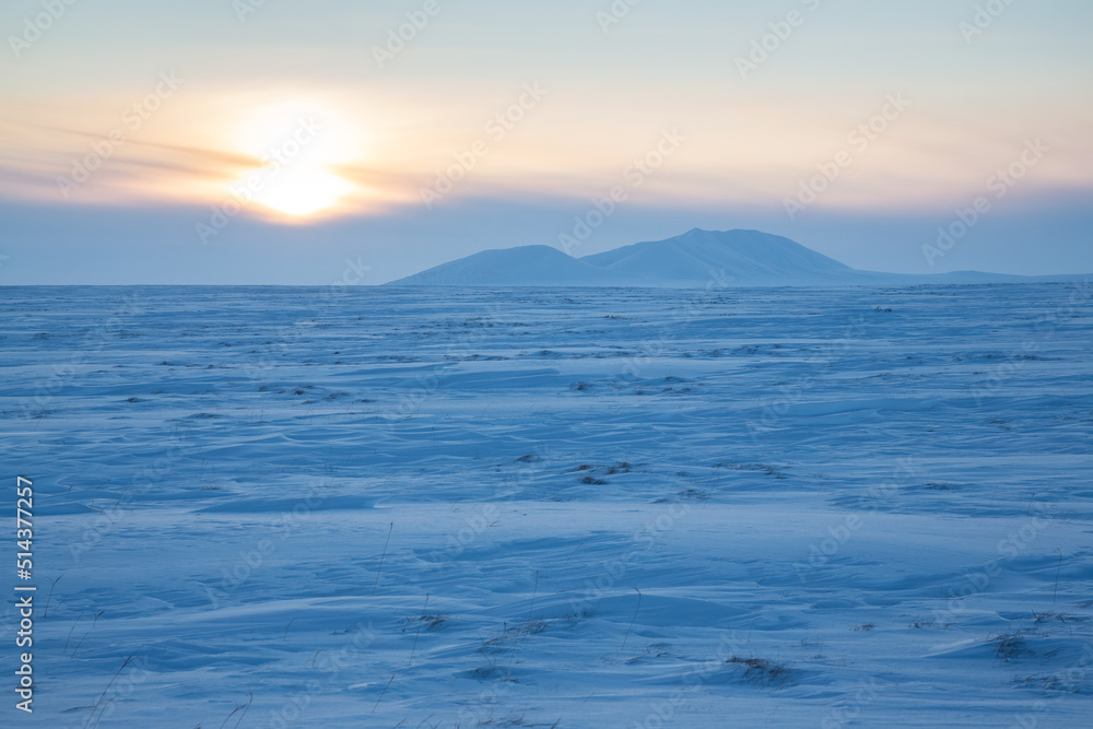Winter arctic landscape. View of the snow-covered tundra and snow-capped mountains. Cold frosty winter weather. Endless Arctic Desert. Northern nature of the polar region. Sunset. Chukotka, Russia. Winter arctic landscape. View of the snow-covered tundra and snow-capped mountains. Cold frosty winter weather. Endless Arctic Desert. Northern nature of the polar region. Sunset. Chukotka, Russia.