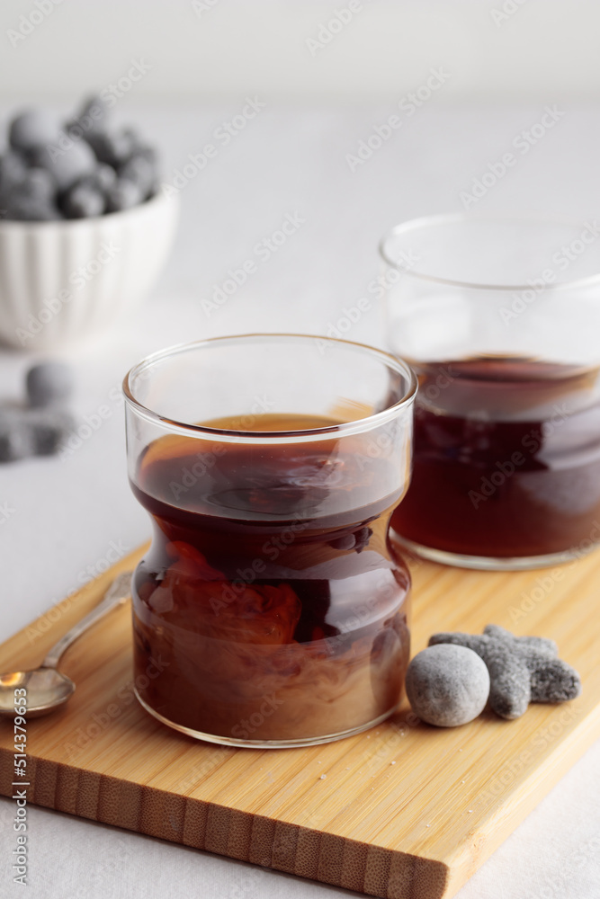 Cups of fresh coffee with milk and a liquorice candies on white table Cups of fresh coffee with milk and a liquorice candies on white table