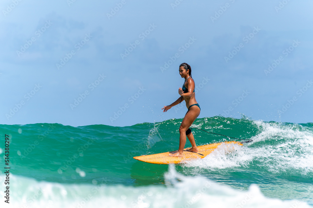 Asian woman surfer surfing and riding surfboard the wave in the sea at tropical beach in sunny day. Healthy female enjoy outdoor activity lifestyle and water sport exercise surfing on summer vacation Asian woman surfer surfing and riding surfboard the wave in the sea at tropical beach in sunny day. Healthy female enjoy outdoor activity lifestyle and water sport exercise surfing on summer vacation