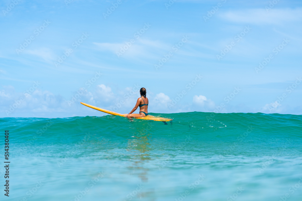 Asian woman surfer surfing and riding surfboard the wave in the sea at tropical beach in sunny day. Healthy female enjoy outdoor activity lifestyle and water sport exercise surfing on summer vacation Asian woman surfer surfing and riding surfboard the wave in the sea at tropical beach in sunny day. Healthy female enjoy outdoor activity lifestyle and water sport exercise surfing on summer vacation