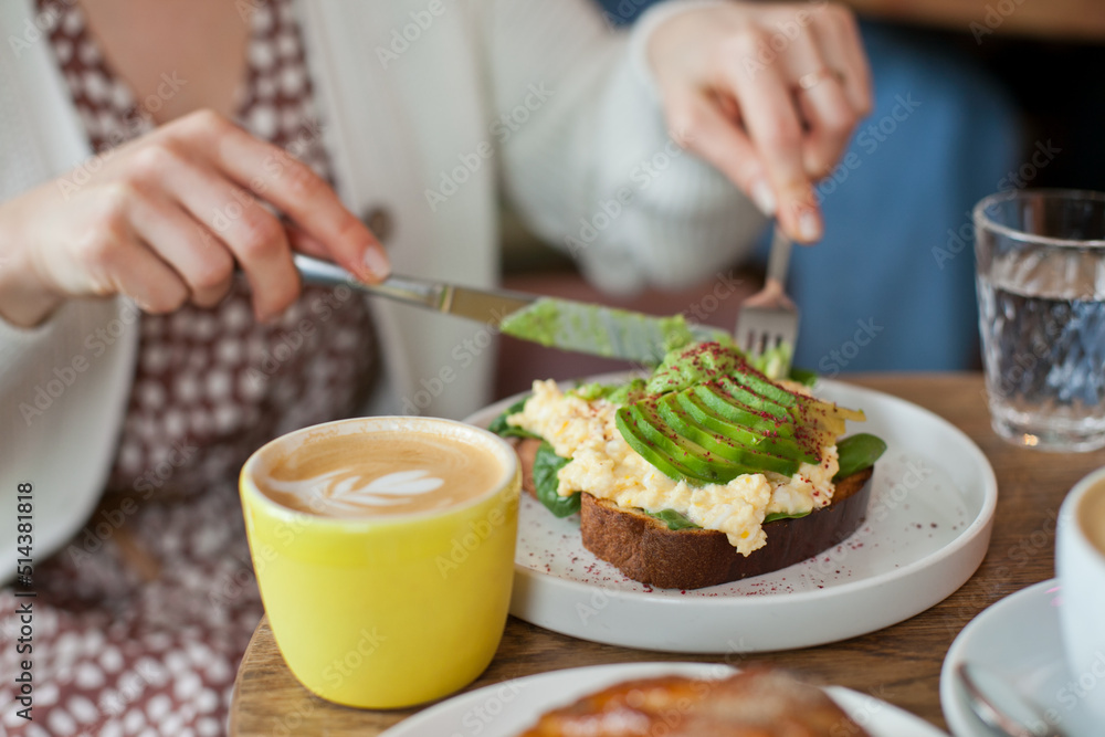 Avocado toast closeup. Young woman at brunch eating and drinking coffee and avocado toast, millennial lifestyle with food. hipster cafe and restaurant. woman at brunch on Sunday.