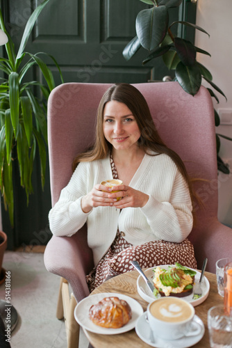 young woman at brunch eating and drinking coffee and avocado toast  millennial lifestyle with food. hipster cafe and restaurant. woman at brunch on weekend with friends