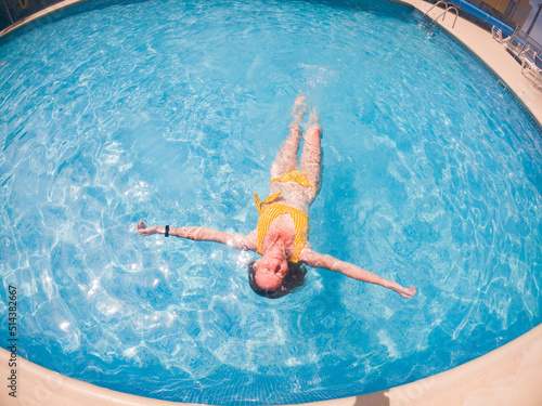 woman in yellow swimming suit in clear blue water in pool