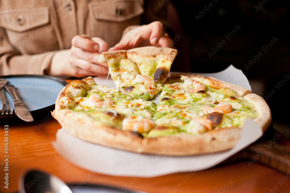 Woman eating pizza at pizzeria. Taking a slice of delicious Italian pizza. Brunch or dinner with friends. fast food. freshly baked pizza