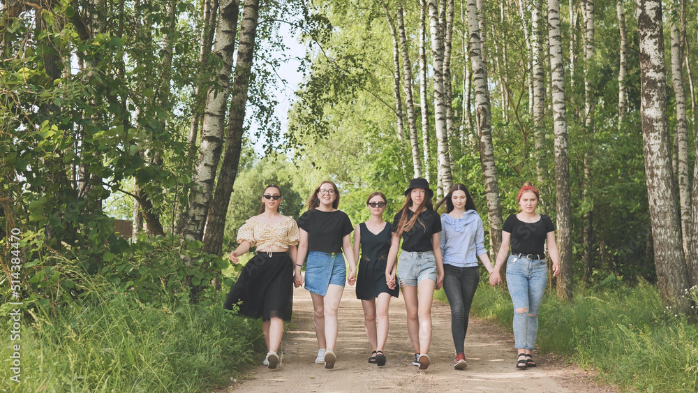 Schoolgirl friends are walking outside the city along a forest road. Schoolgirl friends are walking outside the city along a forest road.