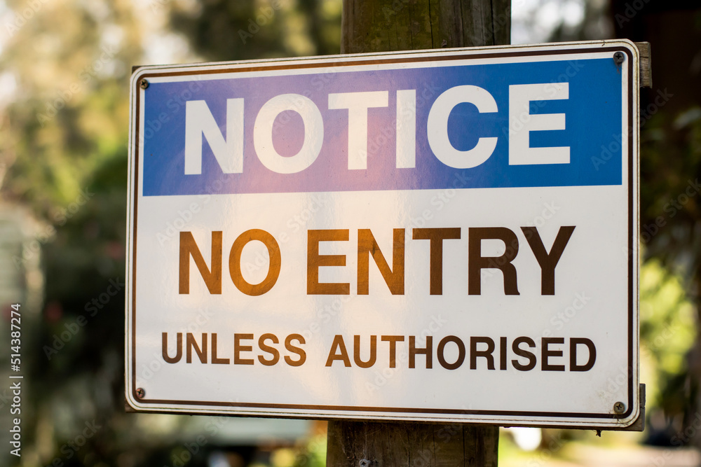 Notice. No entry unless authorised sign on a wooden pole Notice. No entry unless authorised sign on a wooden pole