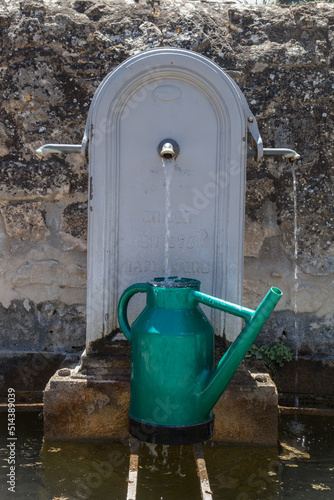 arrosoir vert se remplissant d'eau à une fontaine publique photo