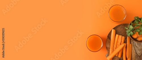 Glasses of fresh carrot juice on orange background with space for text photo