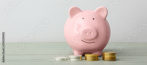 Piggy bank with coins on light background