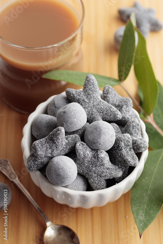 Coffee with liquorice salty salmiakki in a white bowl and a wooden cutting board photo