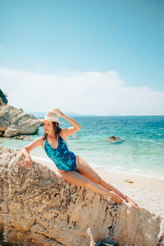 sexy woman in blue swimsuit laying down on the rock at sea beach