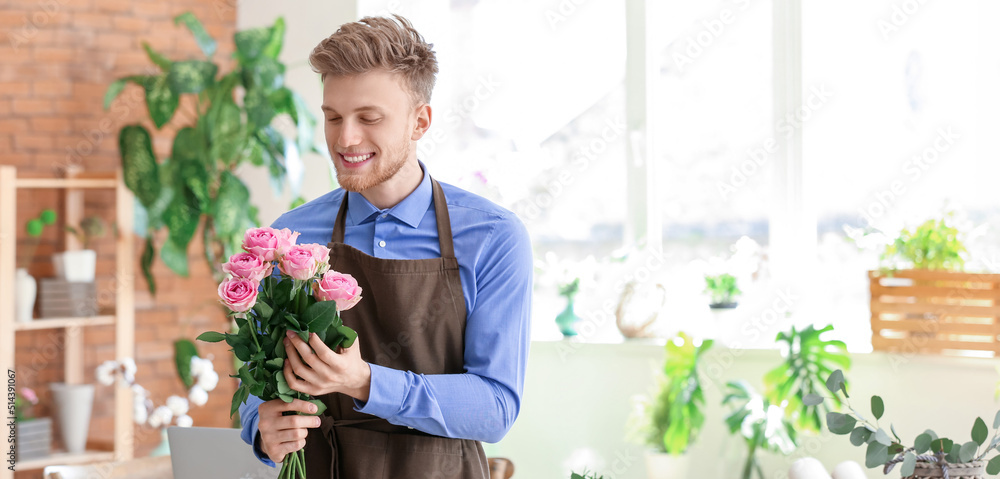 Young male florist with bouquet of roses in shop