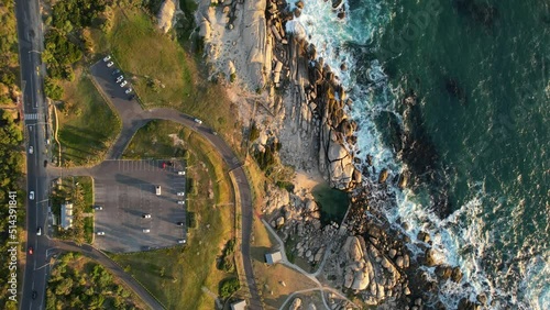 cars driving along coastal road near Maidens Cove Tidal Pool in Cape Town at sunset, aerial
