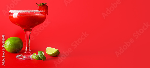 Glass of strawberry daiquiri cocktail and lime on red background with space for text photo