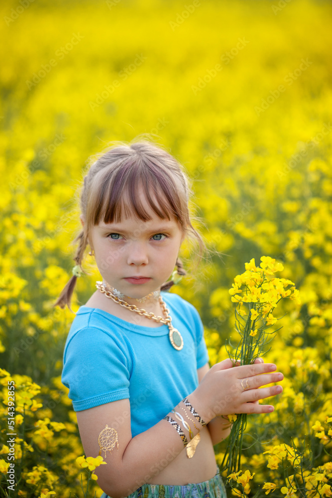 Portrait cute girl with a yellow bouquet of rape flowers in summer on a meadow background. Sweet child with flowers bunch in hands. Portrait cute girl with a yellow bouquet of rape flowers in summer on a meadow background. Sweet child with flowers bunch in hands.
