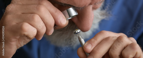 Senior jeweler examining ge...