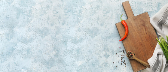 Wooden cutting board with spices on blue background with space for text