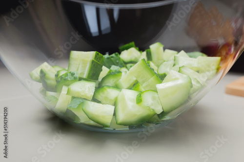 Sliced fresh cucumbers in a glass transparent bowl. Preparing vegetable salad