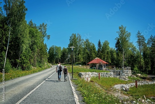 Father and son tourists walk along a mountain forest road in a natural park in northern Europe