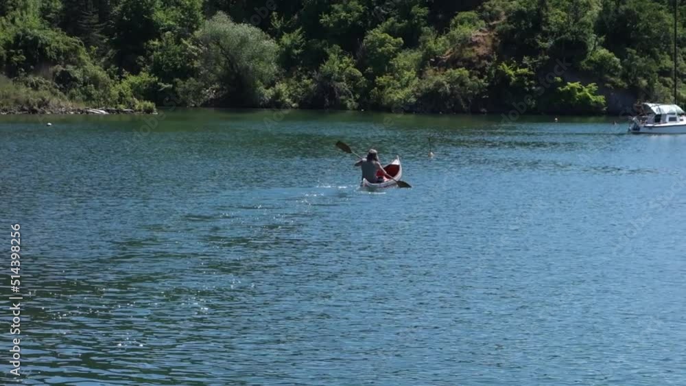 A canoeist is canoeing across the lake to his yacht A canoeist is canoeing across the lake to his yacht