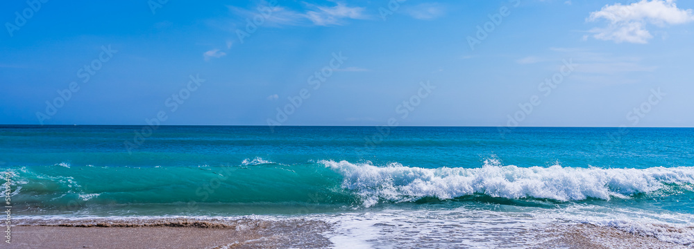 Panorama of a turquoise wave with white foam on a sandy ocean beach in Melbourne Beach, Florida